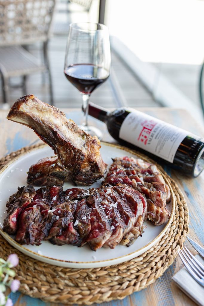 Chuletón a la brasa con vino tinto en la terraza de Marina Bay Palma
