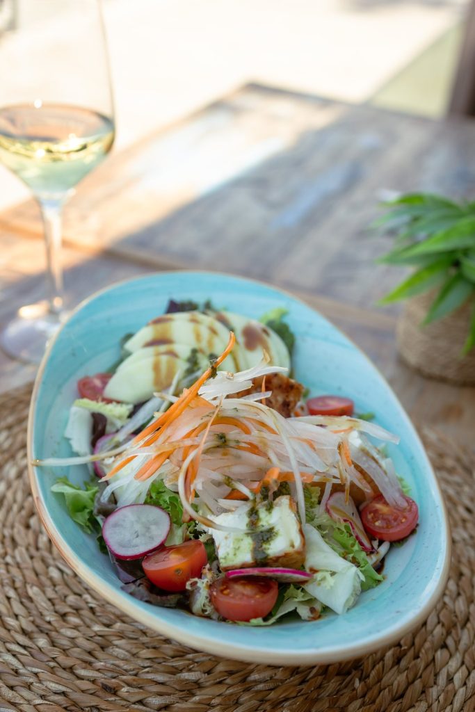 Ensalada fresca y vino blanco en la terraza de Marina Bay Palma